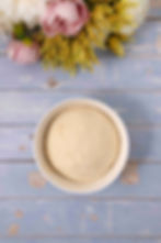 Risen bread dough in a white bowl on a blue background.