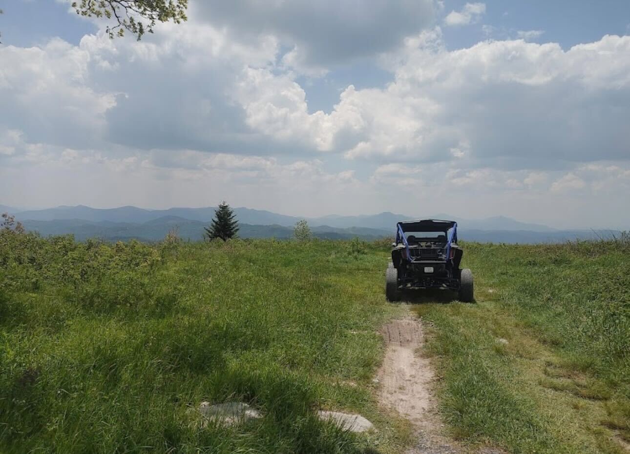 A side-by-side parked on a grassy bald, looking out over the Blue Ridge