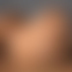 Two capybaras rest on brown soil, their fur fluffed up. A calm water background adds a serene mood. No text is visible.