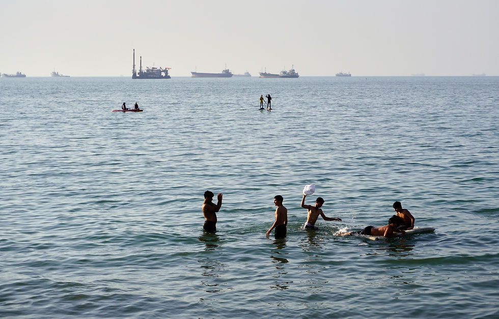 Innbyggere svømmer og leker i vannet i Hormuzstredet mens lasteskip og kommersielle fartøy ligger for anker i det fjerne utenfor Bandar Abbas i Iran, onsdag 10. juni 2026. (Razieh Poudat/ISNA via AP)
