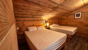 A photo displaying two queen sizd beds in the Pig Pen cabin.