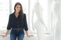 Woman leaning on window sill with mannequins