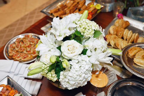 White floral arrangement with appetizers on table