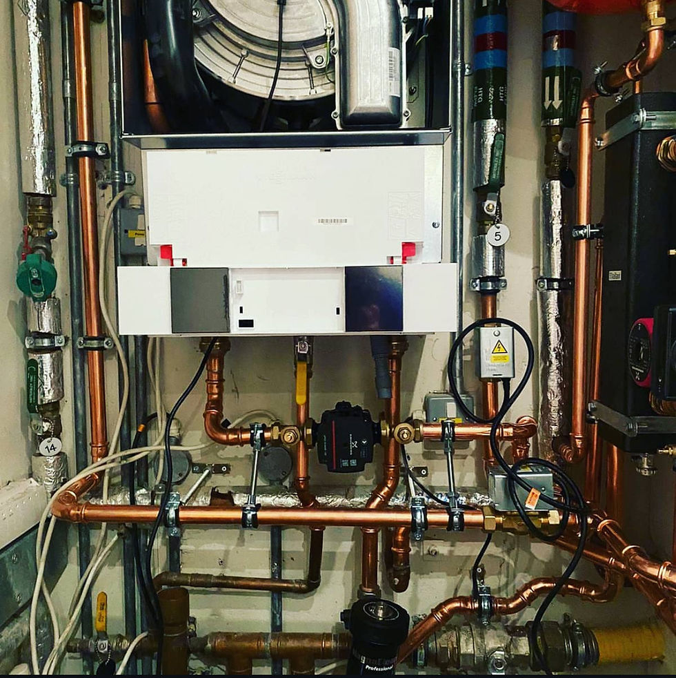 Copper plumbing pipes with a central white boiler unit and various valves and cables. The setting is an enclosed space with a complex system.