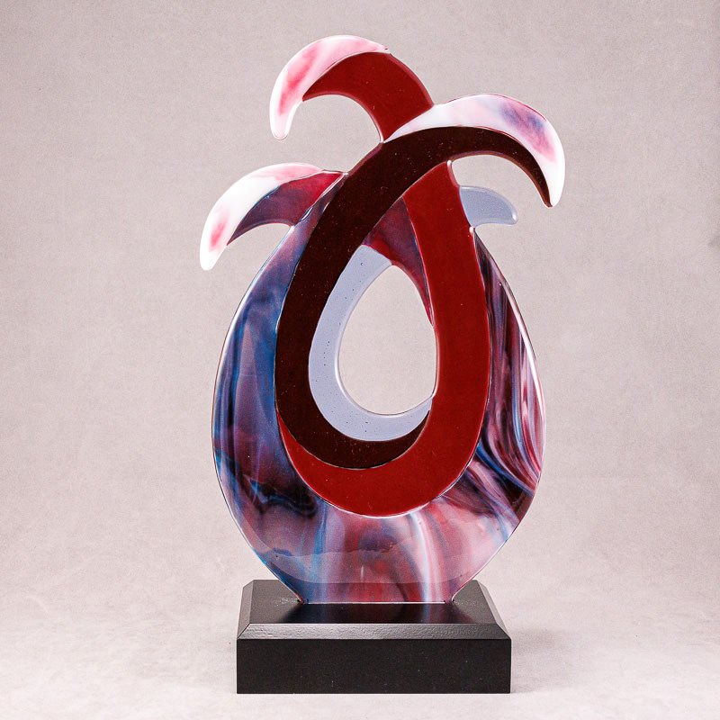 Contemporary glass sculpture with maroons, deep blues and irridescence flowing forms.