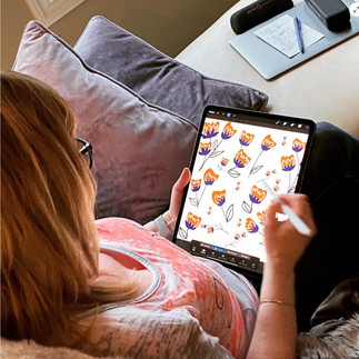 A woman sitting with her Ipad working on a pattern design.