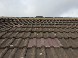 Wavy, brown roof tiles, some patched with lighter tiles