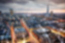 Aerial view of a city at dusk with skyscrapers and illuminated streets.