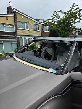 A silver car is parked with a missing windshield, exposing the interior seats