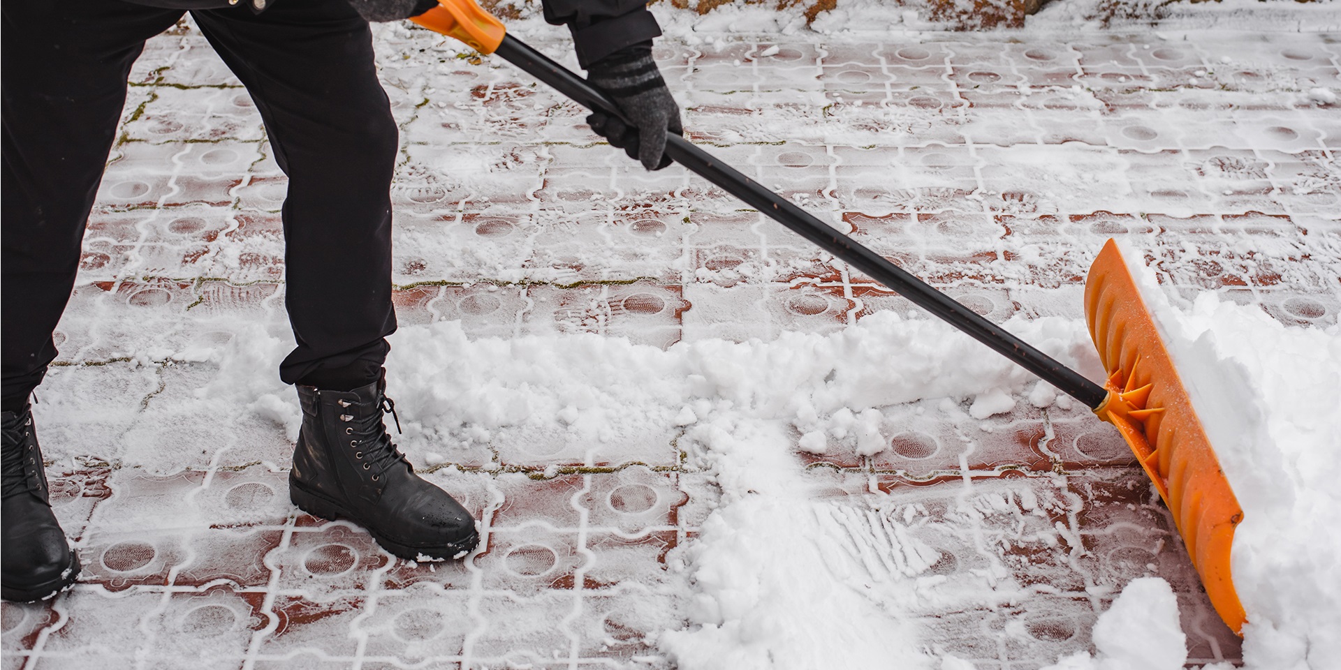 Professional UK worker clearing snow from a residential walkway