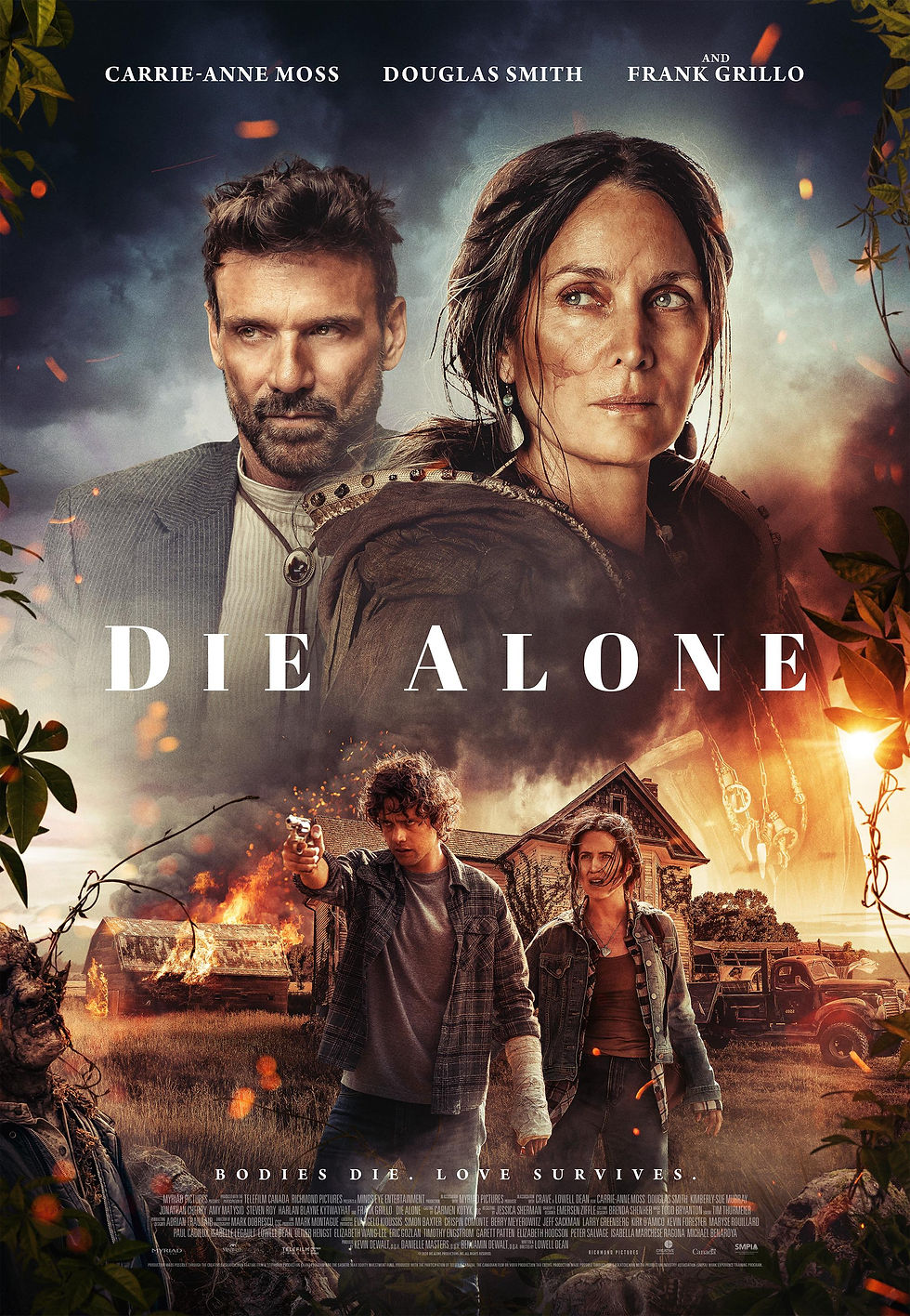 Two people stand in a burning rural setting; one aims a gun. Large faces above, text: "Die Alone." Moody atmosphere, intense colors.