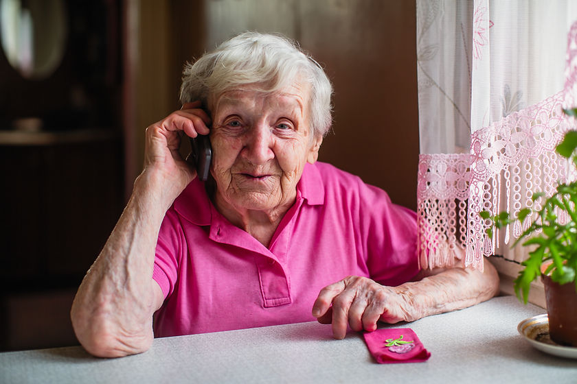 Elderly woman sitting at home and on the phone