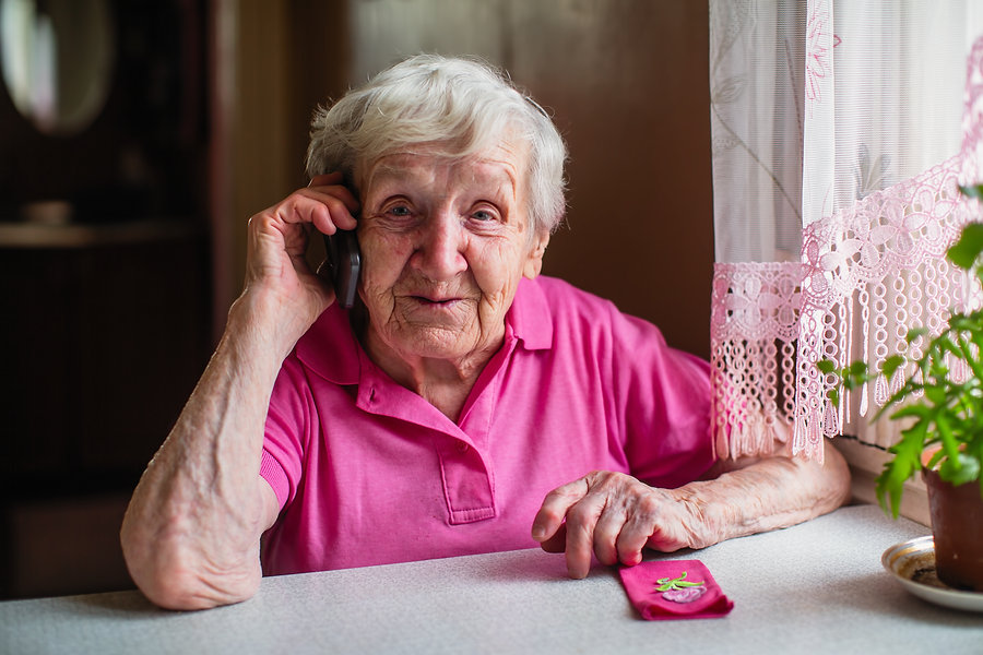 Elderly woman sitting at home and on the phone