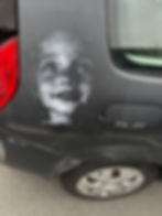 Portrait d’enfant peint sur la carrosserie d’un véhicule brun.