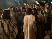 A group of people in robes, one embraces another. Torches light the night. An emotional and historic atmosphere is present.