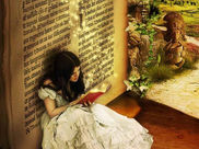 Illustration in which a girl reading a book under the shade of wall in which alphabets are painted