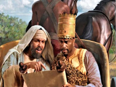 Two men in ancient attire read a scroll on a chariot, one in a crown. Background shows horses and greenery, with a focused and engaged mood.