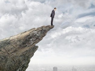 A person standing at the edge of a rock. there is a huge abys before him