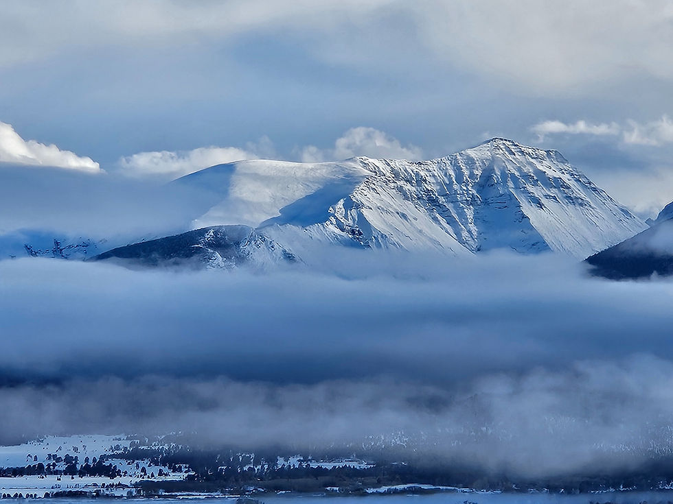 Group of hikers/mountain climbers climbing/hiking on a steep snow slope toward the summit of Mount Elbert in Colorado, wearing raincoats, snowshoes, packs, and ice axes, cold, blue sky, footprints