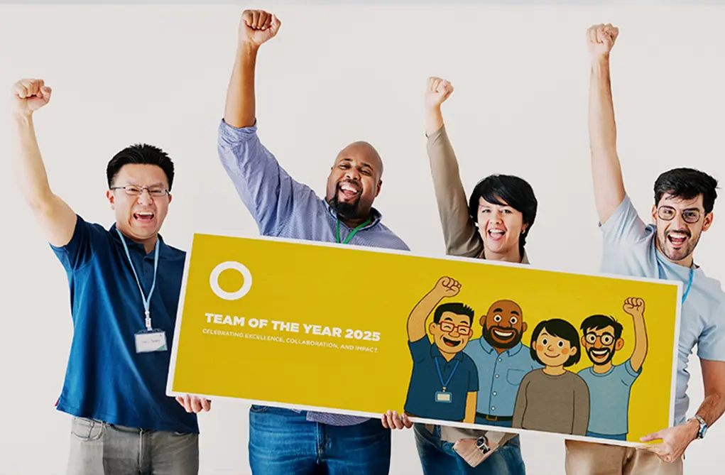 Four diverse team members celebrating with raised fists while holding a custom 'Team of the Year 2025' award banner featuring personalized cartoon illustrations of themselves