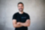 Junger Mann in schwarzem T-Shirt vor einer neutralen Wand