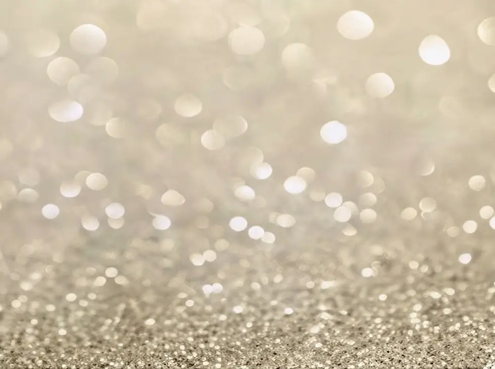 Abstract macro photography of shimmering silver glitter particles. The soft focus creates dreamy, festive, and ethereal bokeh highlights.