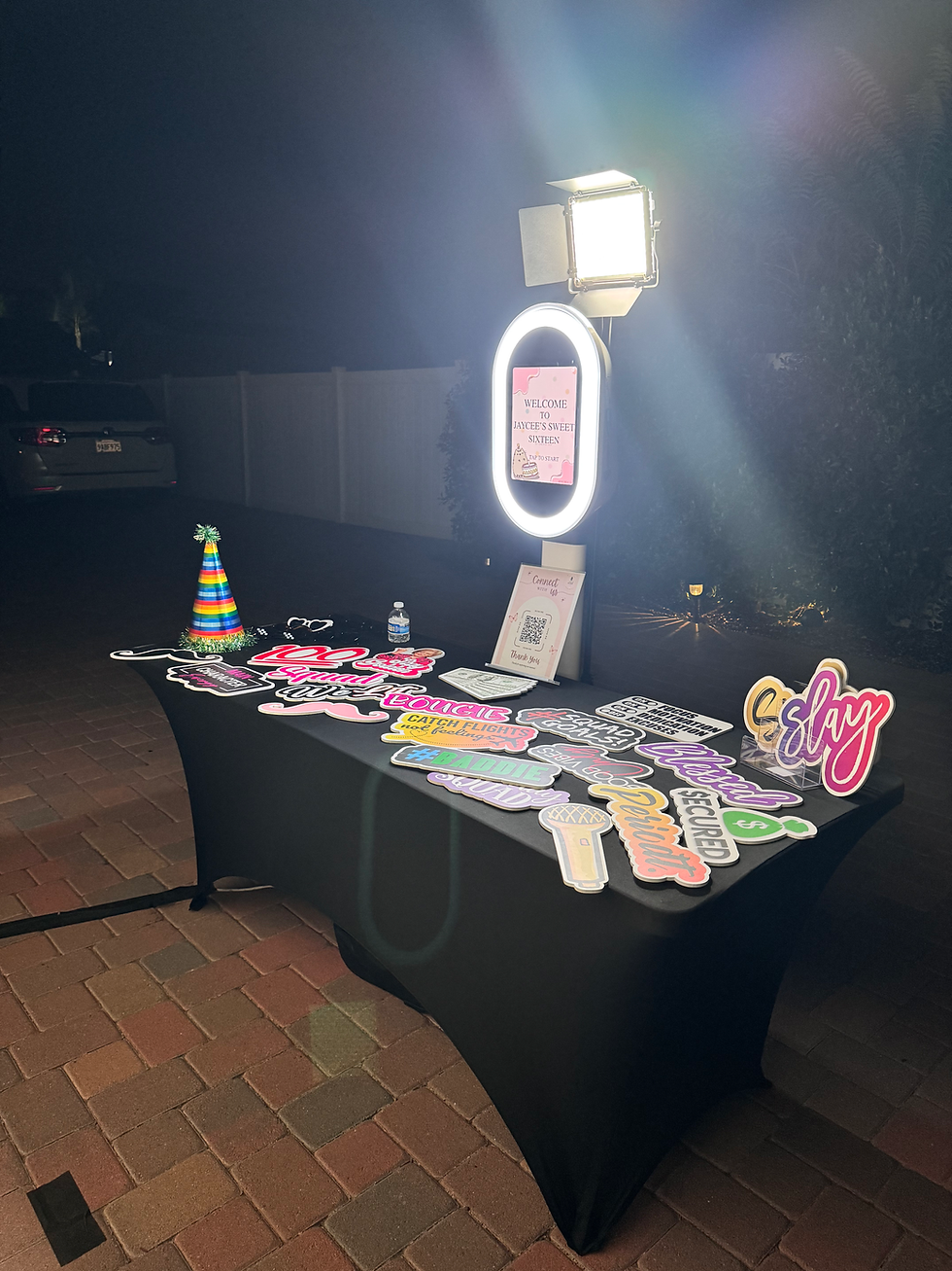 MLOBOOTH photo booth setup with professional lighting, a backdrop, and a prop table.