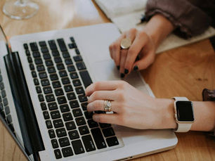 Close-up of a person typing on a MacBook laptop at a workspace