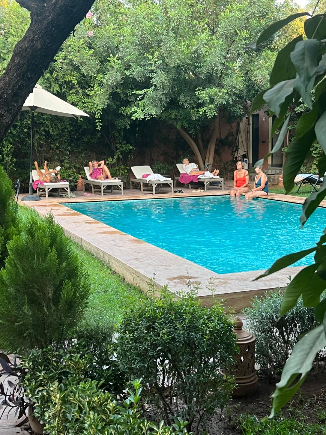 Plusieurs personnes se relaxent au bord d'une piscine, soleil et détente, ALLMOOV MARRAKECH.