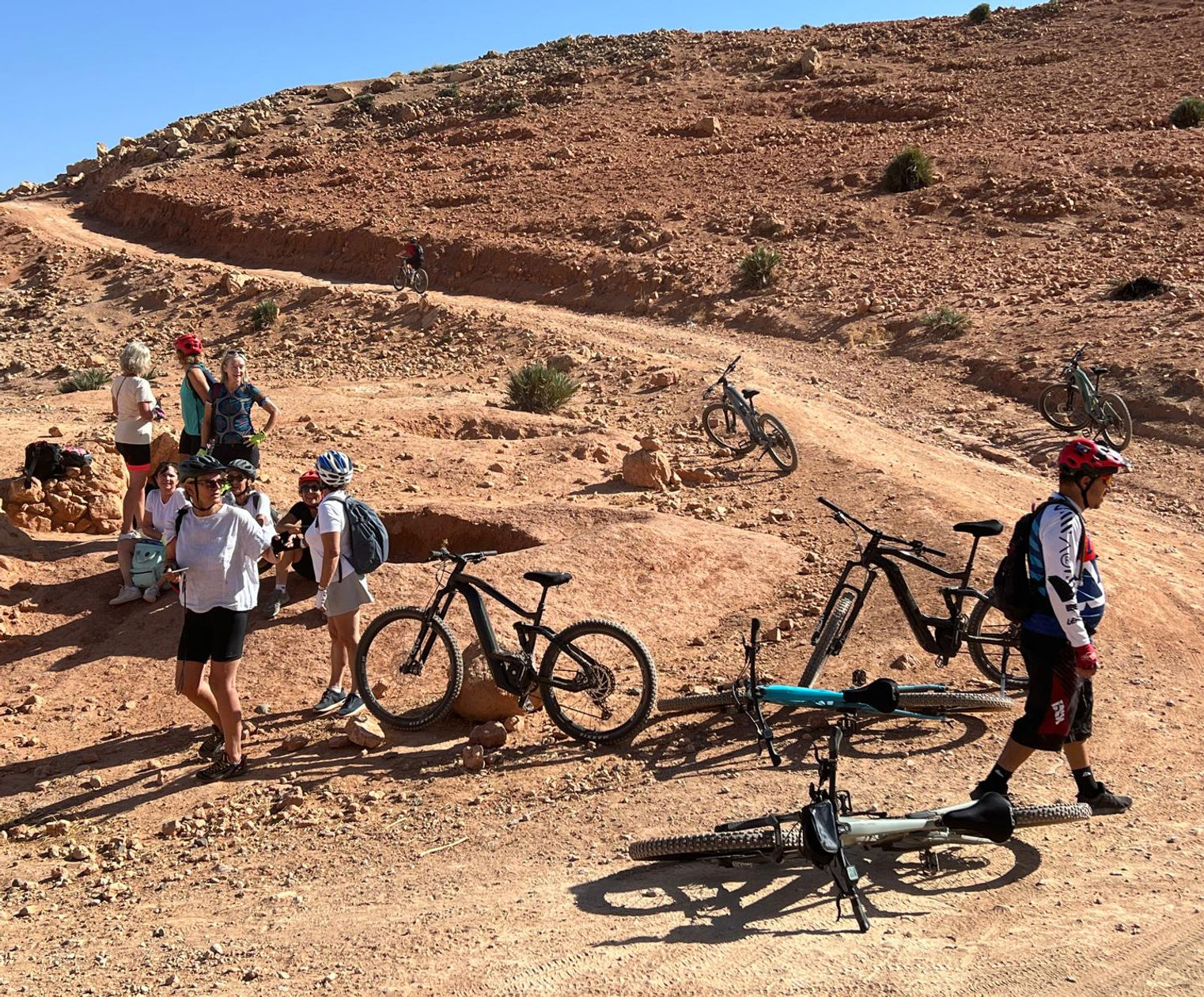 Groupe de personnes et vélos sur un chemin de terre, paysage désertique ALLMOOV MARRAKECH