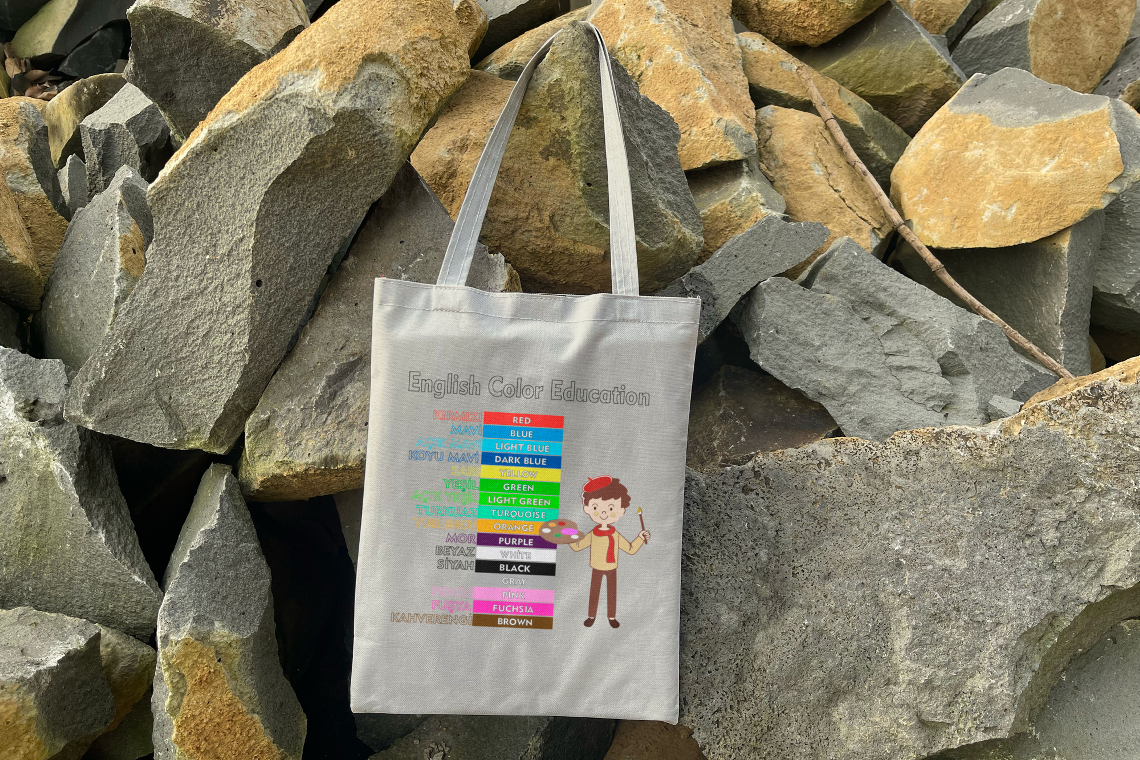 English Colors Information graphic on a tote bag in front of rocks. Bez Çanta & Kanvas Çanta Üreticisi