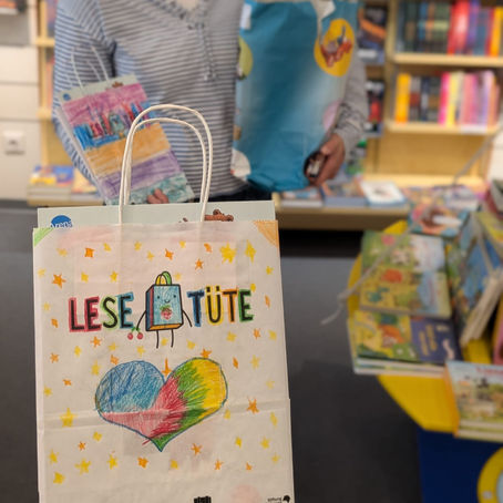 Eine bemalte Papiertüte, in denen sich erstlesebücher befinden