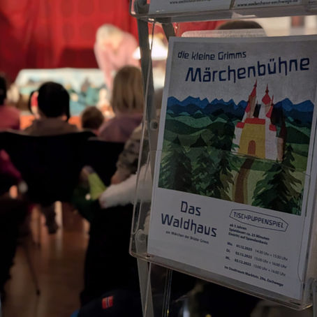 Kinder, die auf eine Bühne schauen und ein Plakat der Märchenbühne im Vordergrund