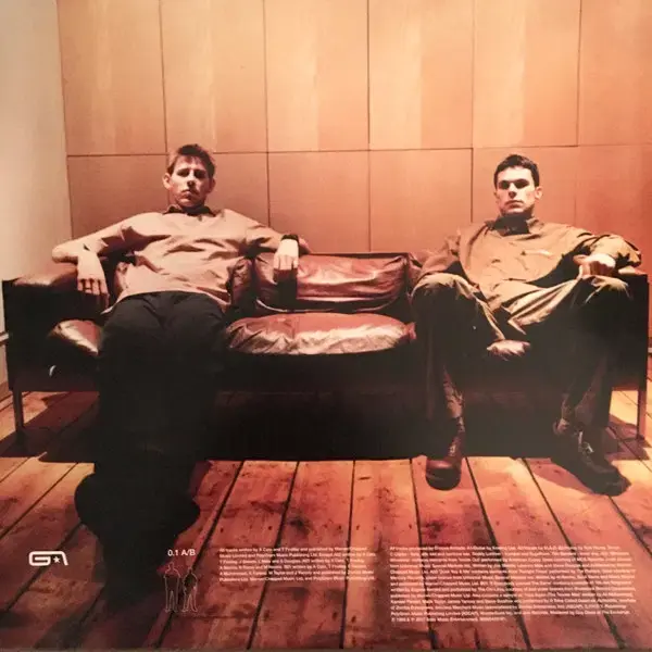 Thumbnail: Two men sitting on a leather sofa in a room with wood paneling.