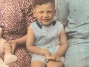 Rabbi Burt Aaron Siegel as a small child sitting in between two family members.
