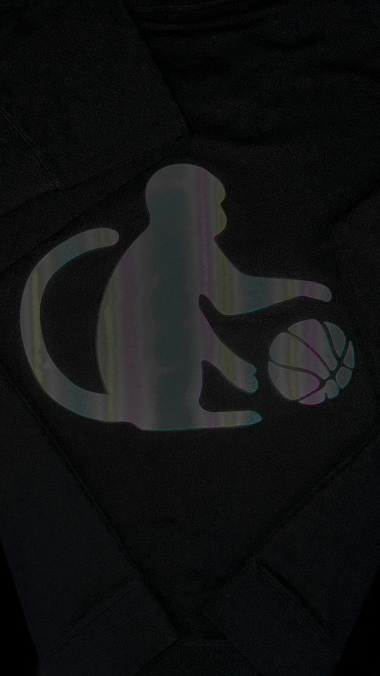 Detail of the reflective monkey logo glowing in low light on the Monkey Balling sweater.