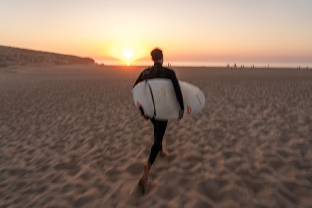 Surfer running to the beach at sunset