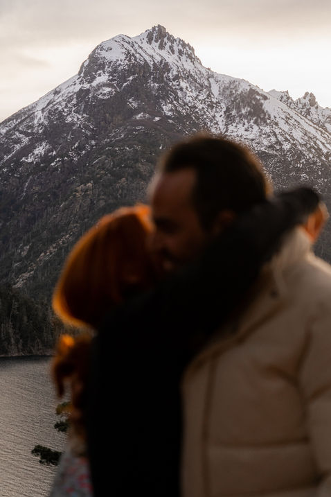 Couple hugging in front of a snow capped mountain