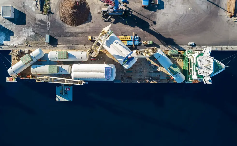 Top down view of a logistics port. Organised containers on the left. Cranes over flowing water on right.