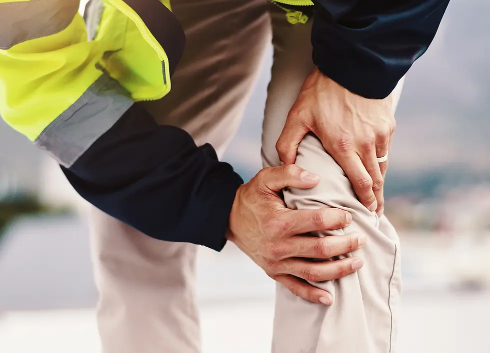 Close-up of hands clutching a knee in pain, with a neon yellow jacket against a blurred outdoor background.