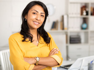 Mexican woman smiling wearing a bright yellow blouse.
