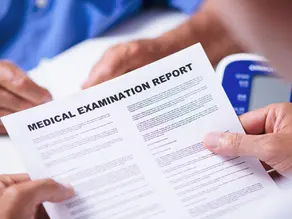 a medical professional holding a document titled Medical Examination Report