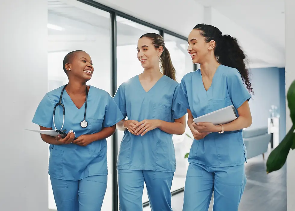 three nurses walking down the hall at the hospital, they are all smiling and talking with each other