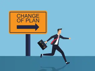 a business man with a briefcase running to the right with a large sign behind him that says "Change of Plan"