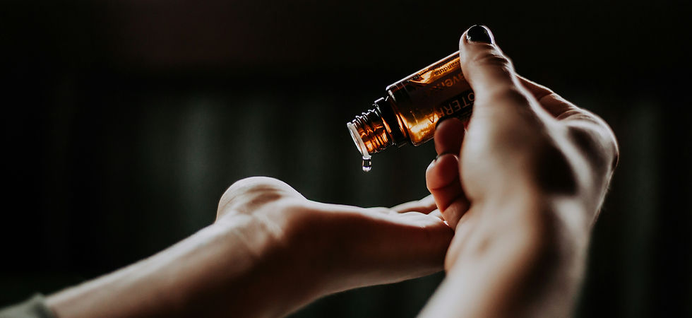 dłonie, nakładanie kropli olejku eterycznego, czarne tło