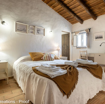 Prepared double bedroom with towels and rustic wooden ceiling.