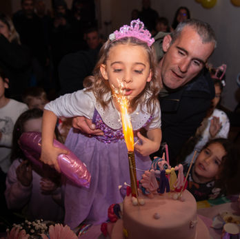 Girl blowing out a sparkler candle on a birthday cake.