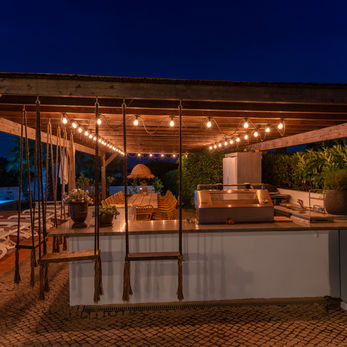 Covered terrace bar and dining area at night in an Algarve guest property.