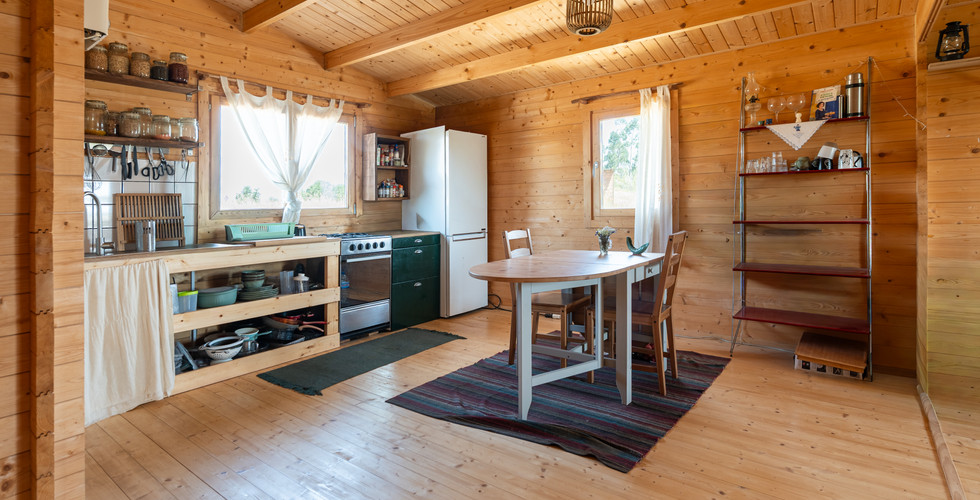The kitchen and open wooden interior show the practical living space inside the off-grid home.