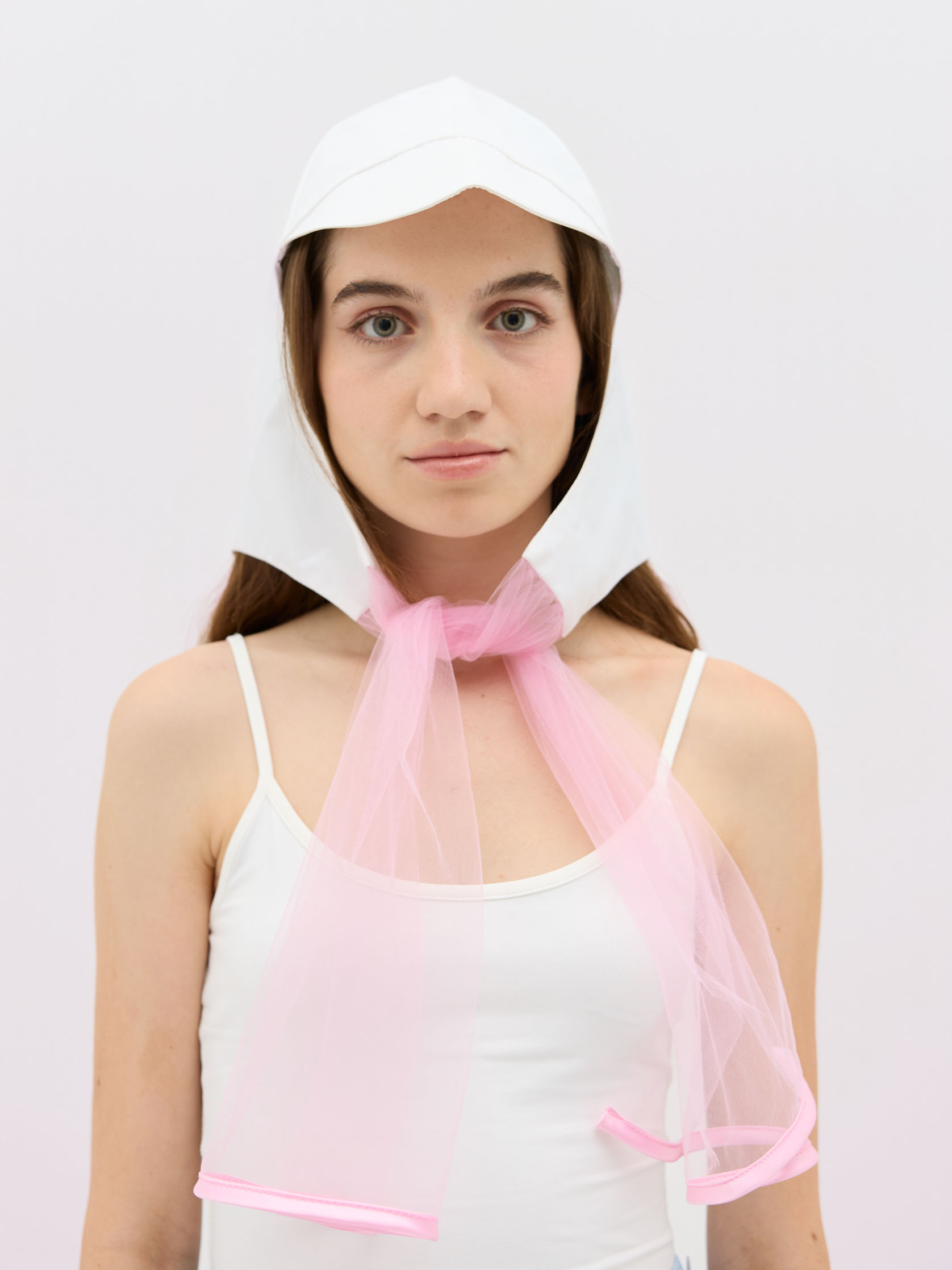 Clochette Babydoll Rose White, transparent White/Pink tulle headpiece worn by a woman, close up front view
